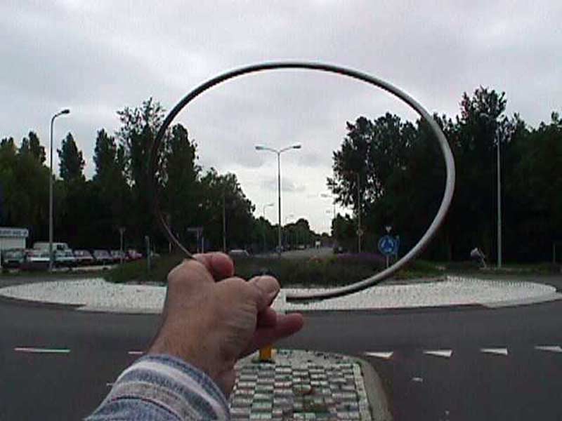 A linear sculpture, an opened circle consisting of two halves joined at the top.